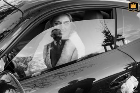 Lille bride, chilled, waits in car with a partially open, reflective window. The groom stands outside, visible in the reflection